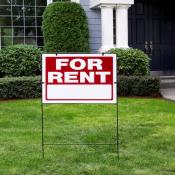 A "For Rent" sign sits in front of a blue single-family home 