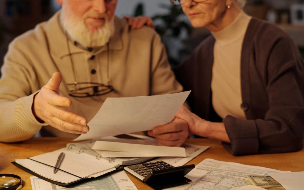 An older couple sits at a table, looking over budget