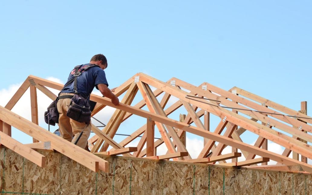 A builder works on the roof of a house.