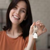 Gen Z woman smiling and holding up house key