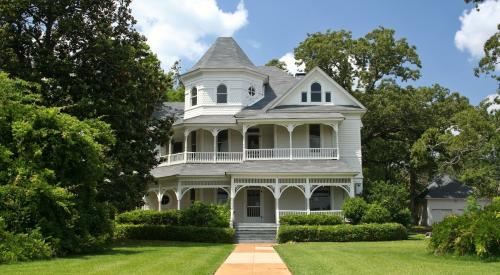 White victorian home sits on large lot lined with trees
