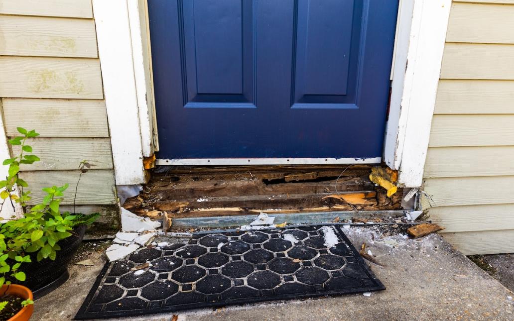 The wooden framing around a doorway is deteriorating