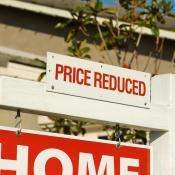 Sign in front of house reading "price reduced"