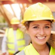Female construction worker carries lumber through jobsite