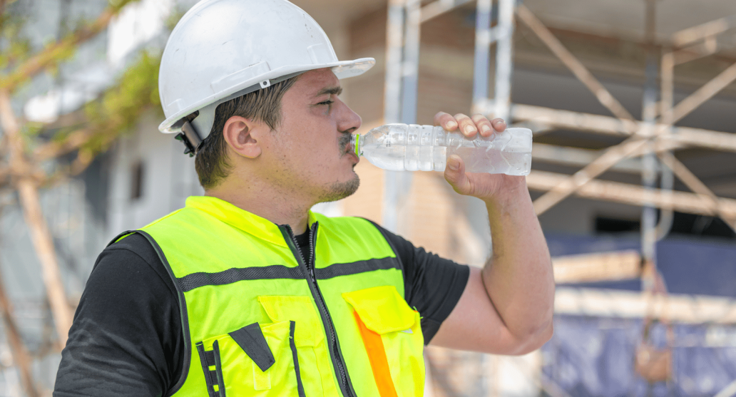Construction worker drinking bottle of water during heat